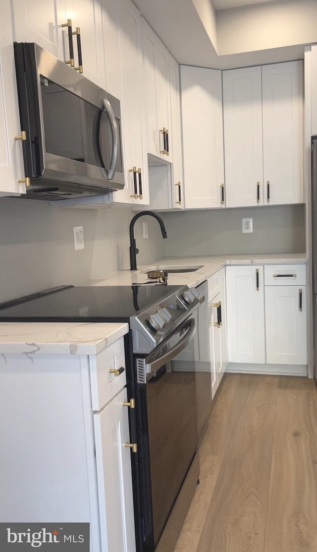 kitchen with range with electric cooktop, light hardwood / wood-style floors, and white cabinets