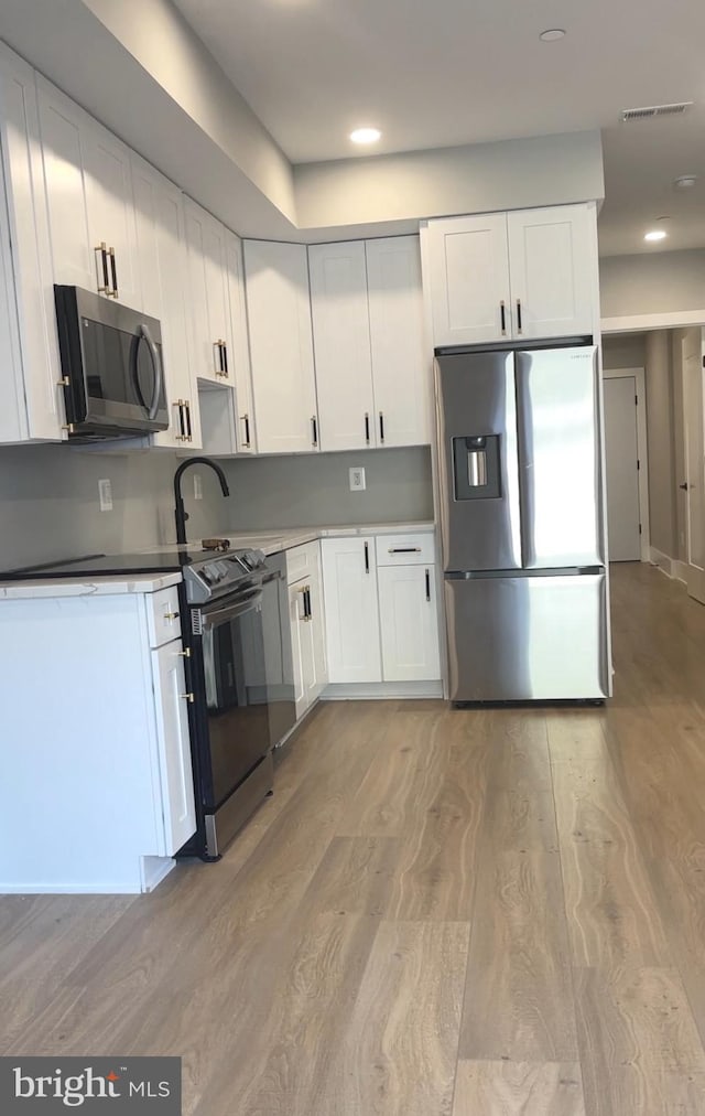 kitchen featuring white cabinets, light hardwood / wood-style flooring, and stainless steel appliances