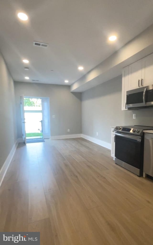 kitchen with white cabinets, light hardwood / wood-style flooring, and stainless steel appliances