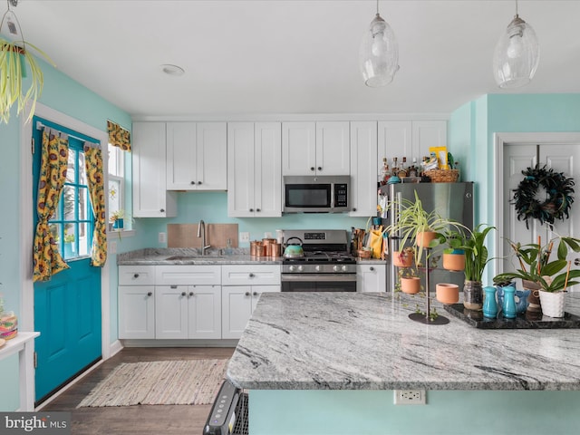 kitchen with decorative light fixtures, white cabinetry, appliances with stainless steel finishes, and sink