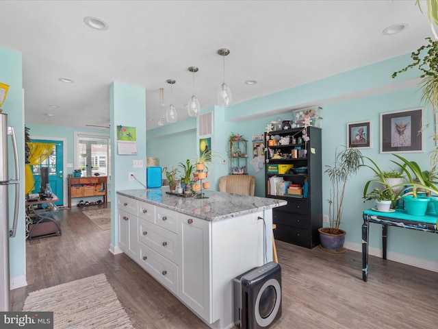 kitchen featuring decorative light fixtures, wood-type flooring, white cabinets, and light stone countertops