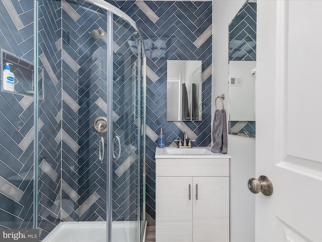 bathroom featuring a shower with shower door and large vanity