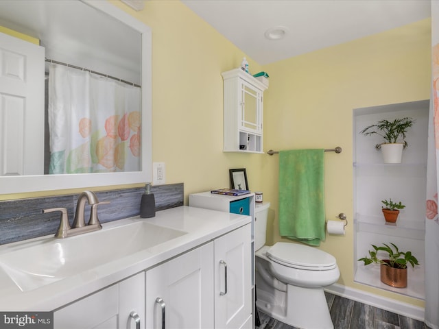 bathroom with toilet, vanity, and hardwood / wood-style floors