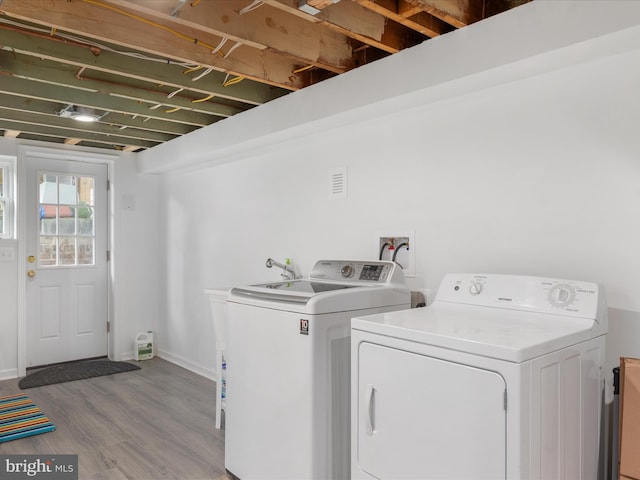 clothes washing area featuring light hardwood / wood-style floors and washer and clothes dryer