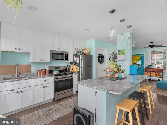 kitchen with white cabinets, appliances with stainless steel finishes, ceiling fan, and dark hardwood / wood-style flooring