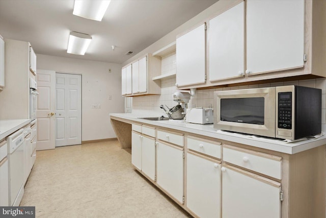 kitchen with white cabinets, backsplash, wall oven, and sink