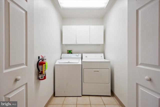 laundry room featuring hookup for a washing machine, washing machine and dryer, light tile floors, and cabinets