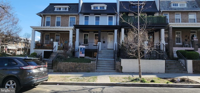 multi unit property with covered porch, brick siding, and stairway