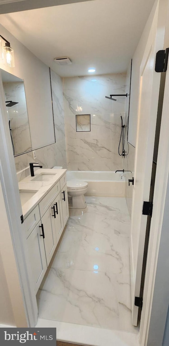 full bathroom featuring vanity, toilet, tiled shower / bath, and tile walls