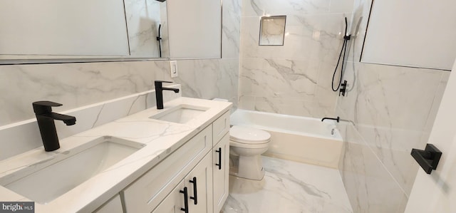 full bathroom featuring toilet, vanity, tiled shower / bath combo, and tile walls