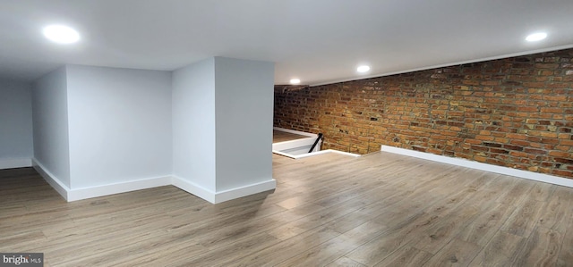 interior space with light hardwood / wood-style flooring, brick wall, and lofted ceiling