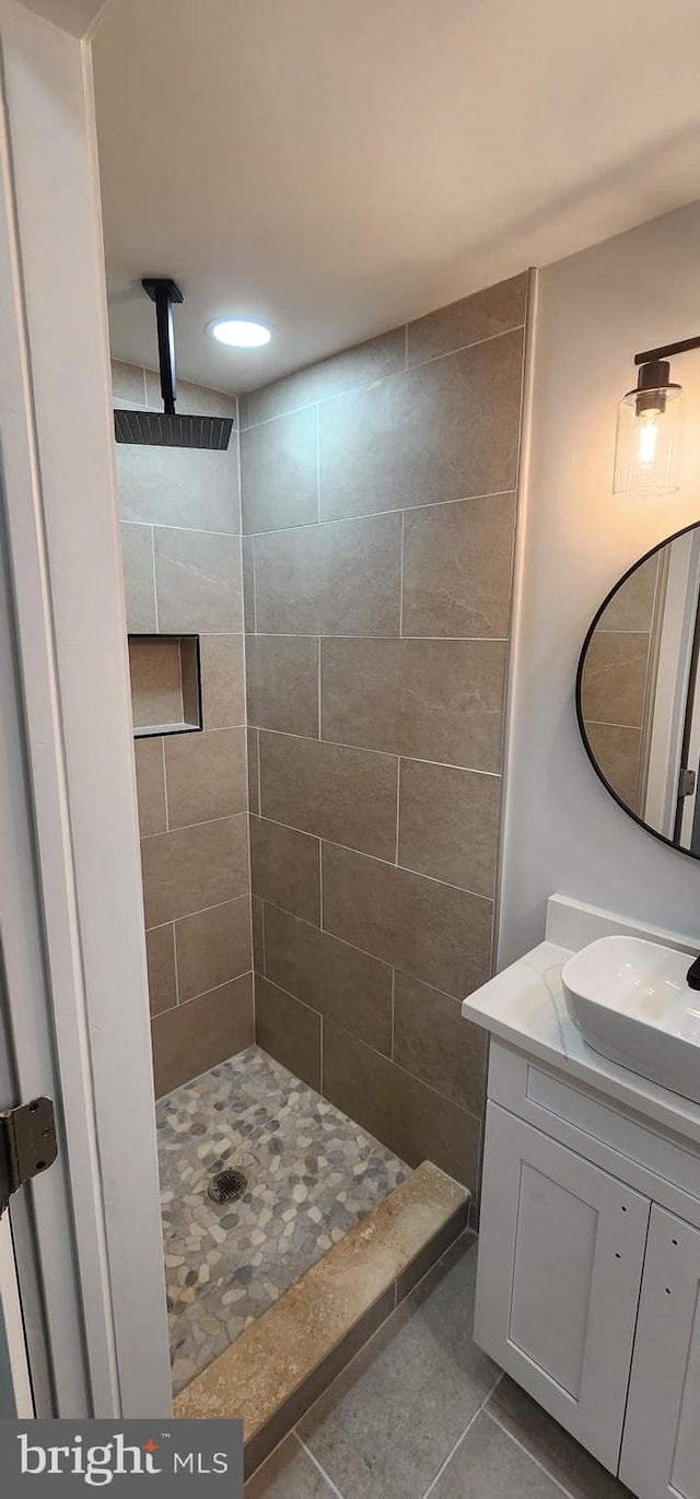 bathroom featuring a tile shower, vanity, and tile patterned floors