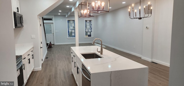 kitchen with a kitchen island with sink, sink, black appliances, and decorative light fixtures