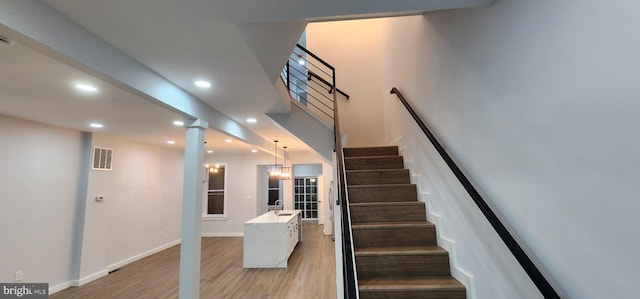 stairs featuring sink and hardwood / wood-style flooring