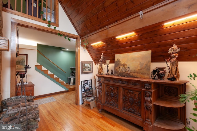 hall featuring light hardwood / wood-style floors, vaulted ceiling, and wooden ceiling