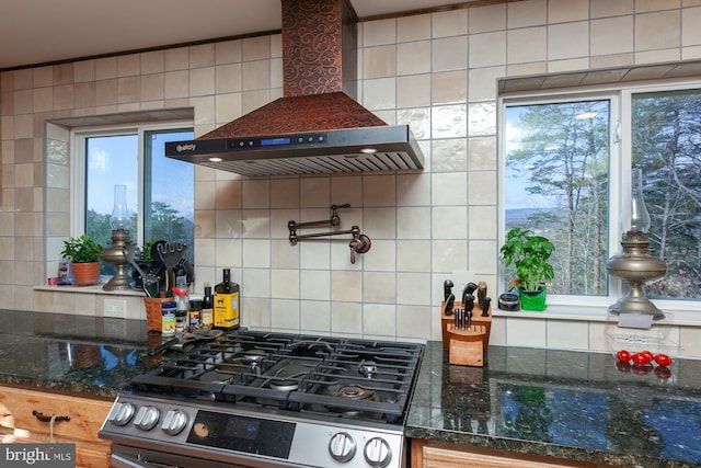 kitchen featuring stove, tasteful backsplash, a wealth of natural light, and wall chimney exhaust hood