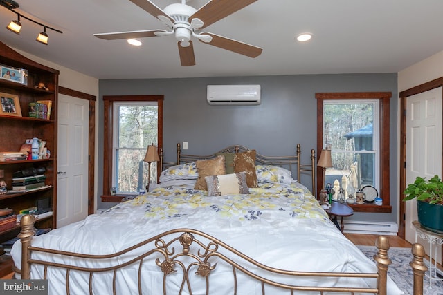 bedroom featuring ceiling fan, wood-type flooring, baseboard heating, and an AC wall unit