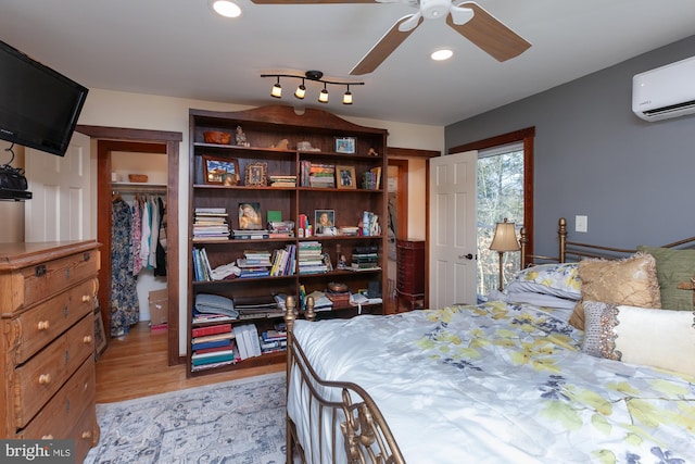 bedroom with ceiling fan, a closet, a wall unit AC, and light hardwood / wood-style flooring