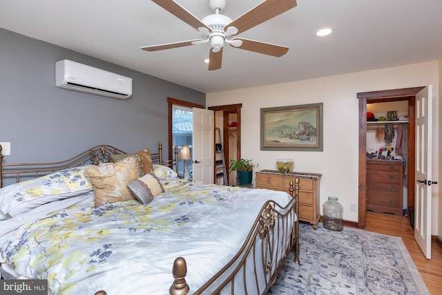 bedroom featuring a closet, light hardwood / wood-style flooring, ceiling fan, and a wall unit AC