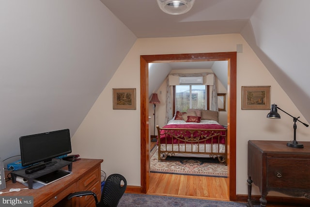 bedroom featuring lofted ceiling, wood-type flooring, and an AC wall unit