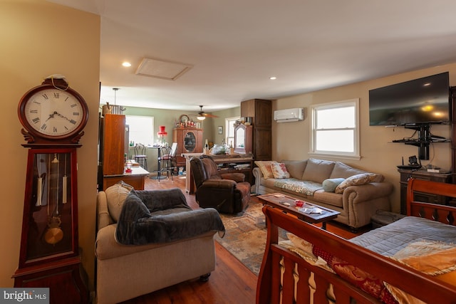 living room with a wall unit AC, ceiling fan, and hardwood / wood-style flooring