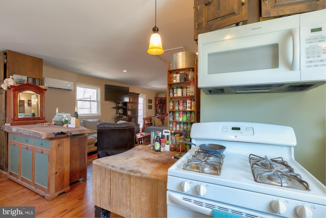 kitchen featuring pendant lighting, white appliances, light hardwood / wood-style flooring, and a wall unit AC