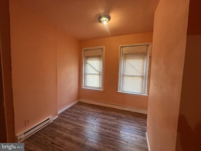 unfurnished room with baseboard heating and dark wood-type flooring