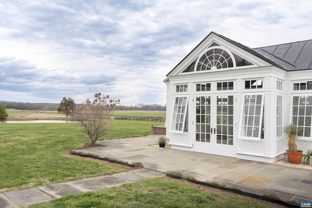 exterior space featuring french doors, a rural view, and a lawn