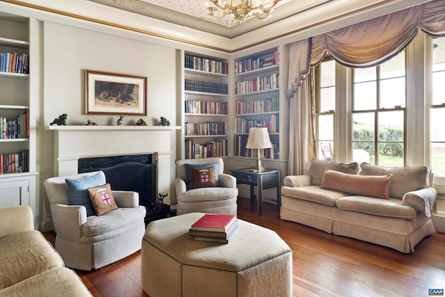 sitting room with crown molding, built in features, and hardwood / wood-style flooring