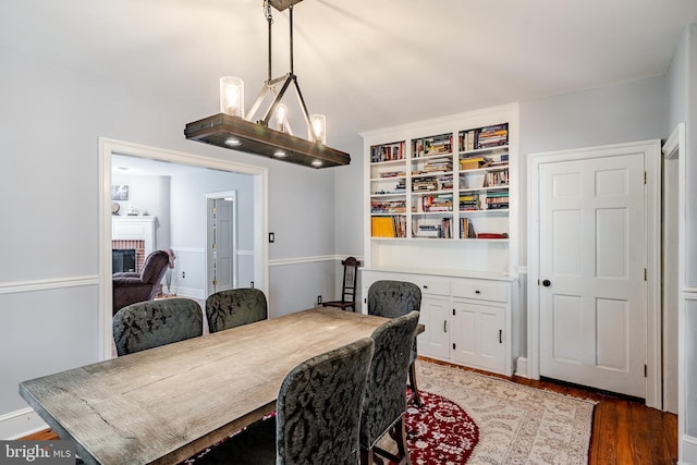 dining space featuring dark hardwood / wood-style flooring, a notable chandelier, and a fireplace