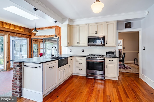 kitchen featuring pendant lighting, hardwood / wood-style floors, appliances with stainless steel finishes, backsplash, and sink