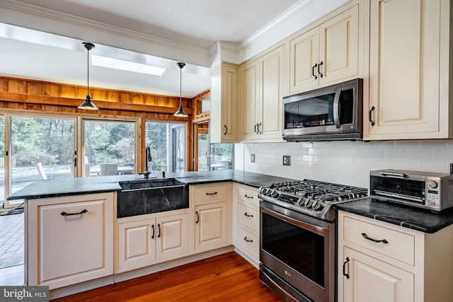 kitchen featuring kitchen peninsula, appliances with stainless steel finishes, backsplash, decorative light fixtures, and light wood-type flooring