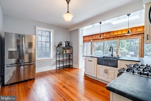 kitchen with stainless steel fridge with ice dispenser, light hardwood / wood-style flooring, white cabinets, hanging light fixtures, and sink