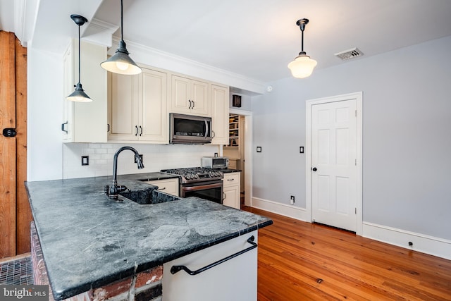 kitchen with hanging light fixtures, backsplash, wood-type flooring, and stainless steel appliances