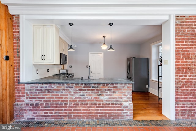 kitchen featuring pendant lighting, light hardwood / wood-style flooring, backsplash, stainless steel refrigerator, and sink