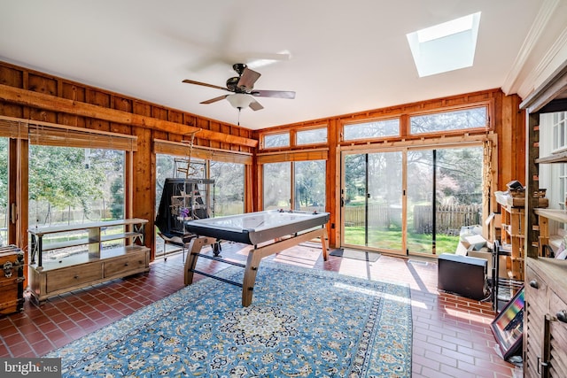 recreation room with wooden walls, a skylight, and a healthy amount of sunlight