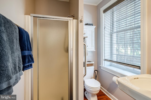 bathroom featuring toilet, ornamental molding, a shower with shower door, and wood-type flooring