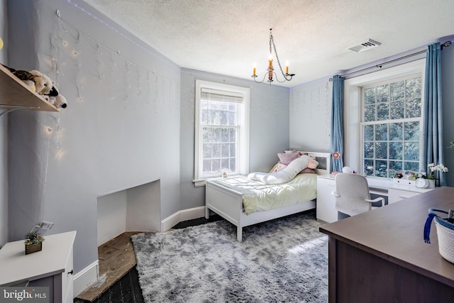 bedroom featuring a textured ceiling, a chandelier, and multiple windows