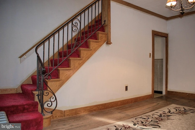 stairway with crown molding, a chandelier, and hardwood / wood-style flooring