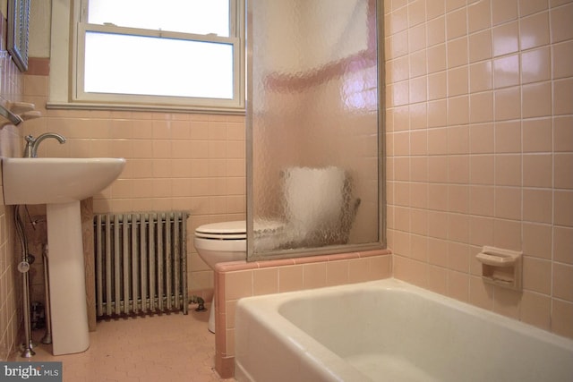 bathroom featuring tile flooring, toilet, tile walls, and radiator