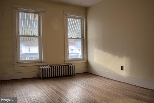 unfurnished room featuring radiator heating unit and light wood-type flooring