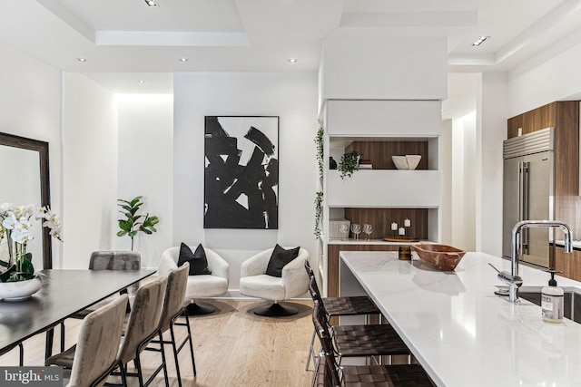 dining area with a raised ceiling, sink, and wood-type flooring