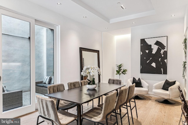 dining room featuring a raised ceiling and light hardwood / wood-style flooring