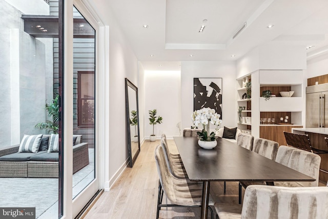 dining room with a raised ceiling and light hardwood / wood-style flooring