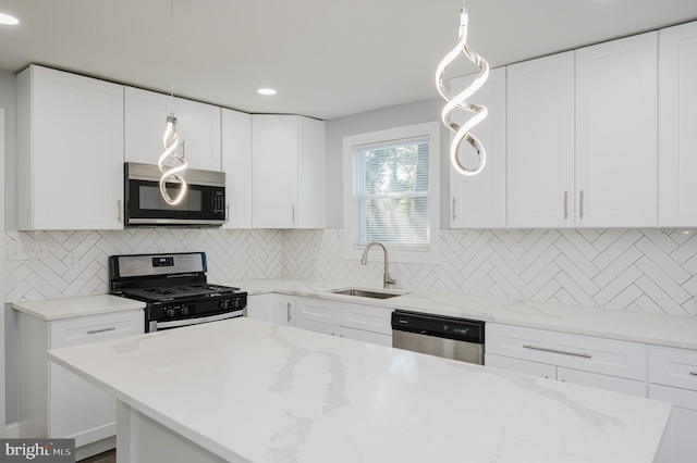 kitchen with decorative backsplash, white cabinetry, decorative light fixtures, and stainless steel appliances