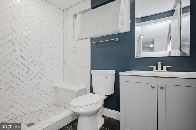 bathroom featuring vanity, toilet, tile patterned floors, and tiled shower