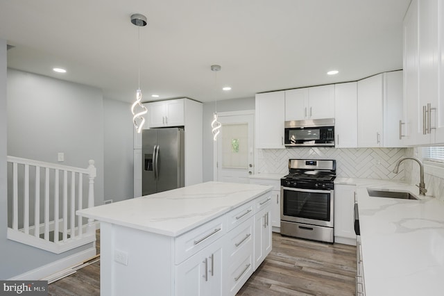 kitchen featuring wood-type flooring, sink, a center island, hanging light fixtures, and stainless steel appliances