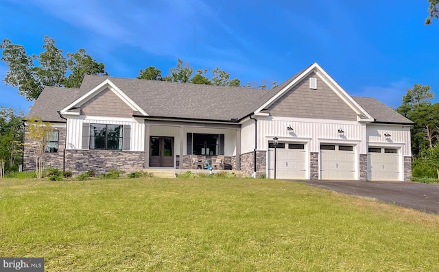 view of front of property featuring a garage, covered porch, and a front yard