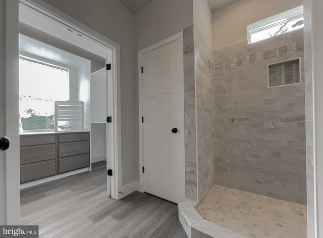 bathroom featuring hardwood / wood-style flooring, tiled shower, and a wealth of natural light