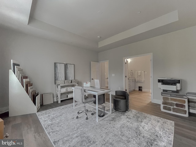 office area with heating unit, a tray ceiling, and dark hardwood / wood-style floors